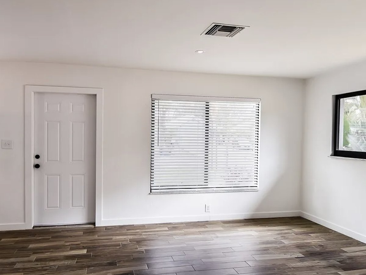 The renovated living room with a new front door, replacement windows and new plank flooring throughout.