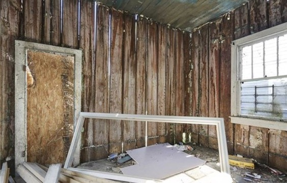 An interior corner stripped back: solid vertical planks running floor to ceiling as the wall itself, with no studs and no cavity behind them.