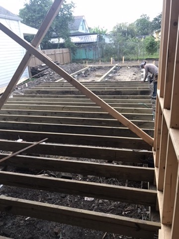 New floor joists running across the block piers, framing out the deck of the rear extension.