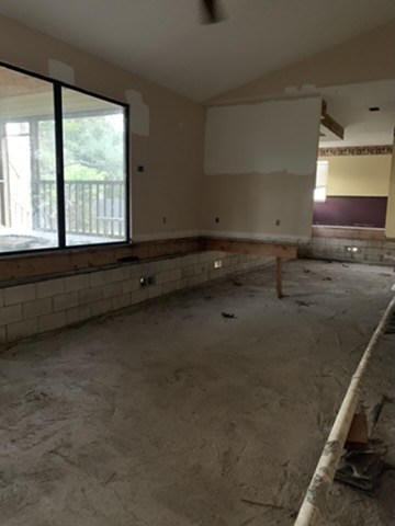 The living area with the subfloor gone, open ground below, block courses running along the base of the walls and the original wood framing above.