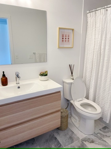 The completed bathroom: a floating wood vanity with a vessel-style basin, framed mirror and tiled floor.